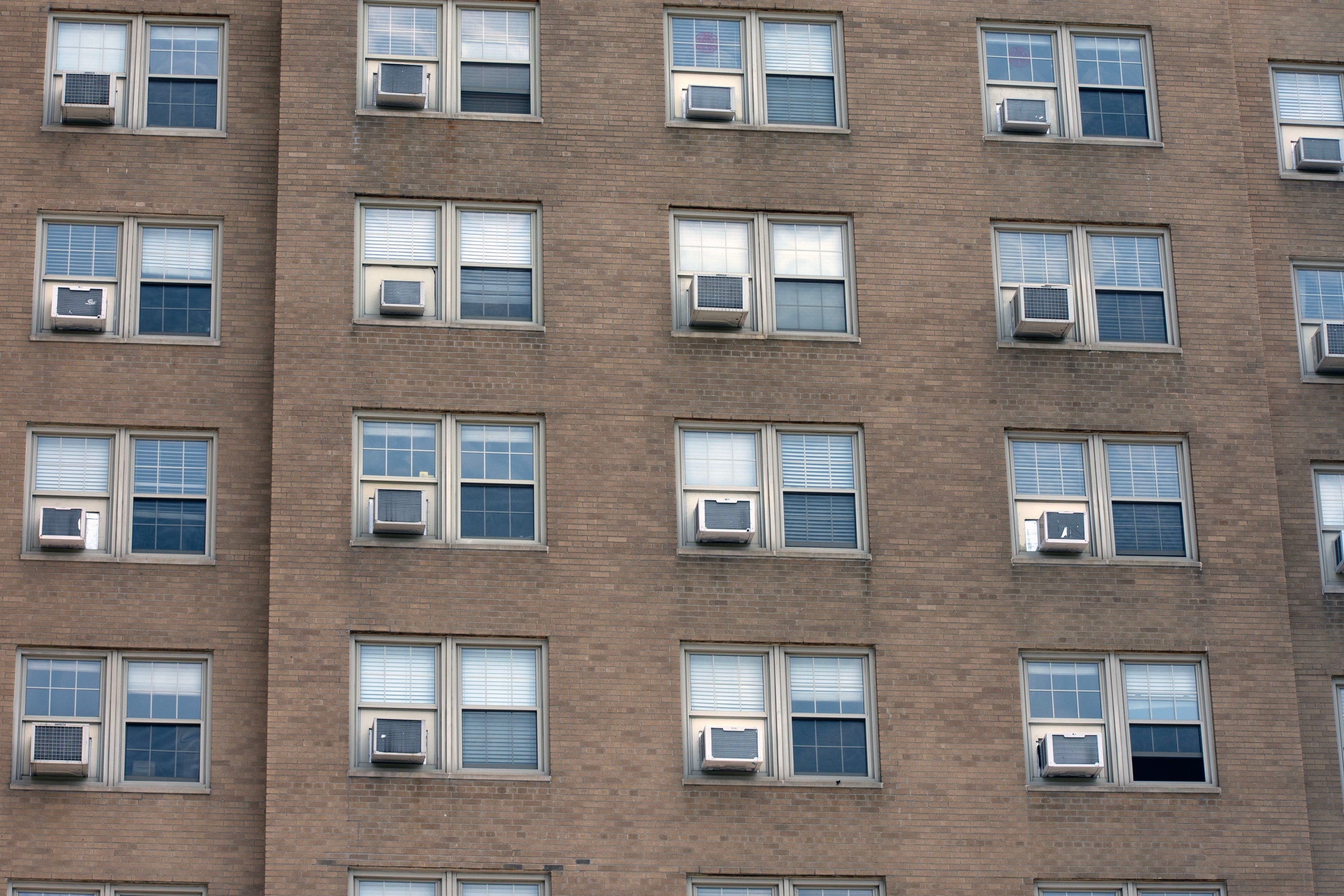 Row of windows on a building facade with air conditioning units.
